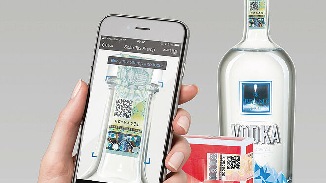 Imagen de una mano que sostiene un teléfono móvil y escaneado del código QR en una etiqueta segura en una botella de alcohol.